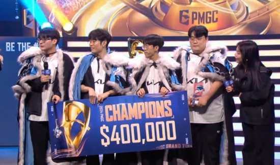 D Plus KIA team celebrating their victory at PMGC 2024, holding a Champions banner and a $400,000 prize check on stage, wearing their team jerseys and victory capes.