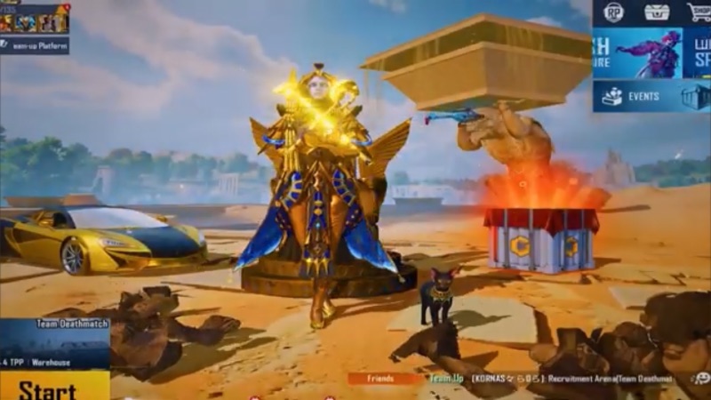 A character in a glowing gold and blue outfit stands in PUBG Mobile's lobby with a gold car, a black cat, and a supply crate in the background.